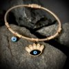 a bamboo look cuff kada bracelet with evil eye hanging chars a magnetic closure and rose gold finish by silly owl