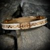 channel symbol with studded diamonds and an embossed checkered design on a rsoe gold finish cuff kada bracelet bangle unisex by silly owl